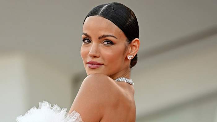 Sofia Resing smiles over her shoulder wearing a diamond necklace and a series of diamond earrings.